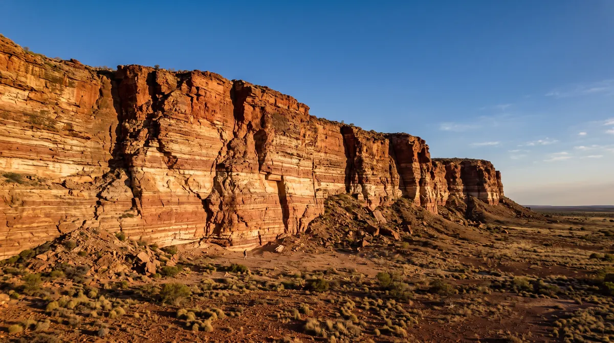 Towering cliffs of layered red and ochre rock in the Australian outback at golden hour